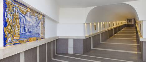 Un pasillo moderno de hotel con una escalera larga y recta y un mural decorativo de azulejos en la pared.