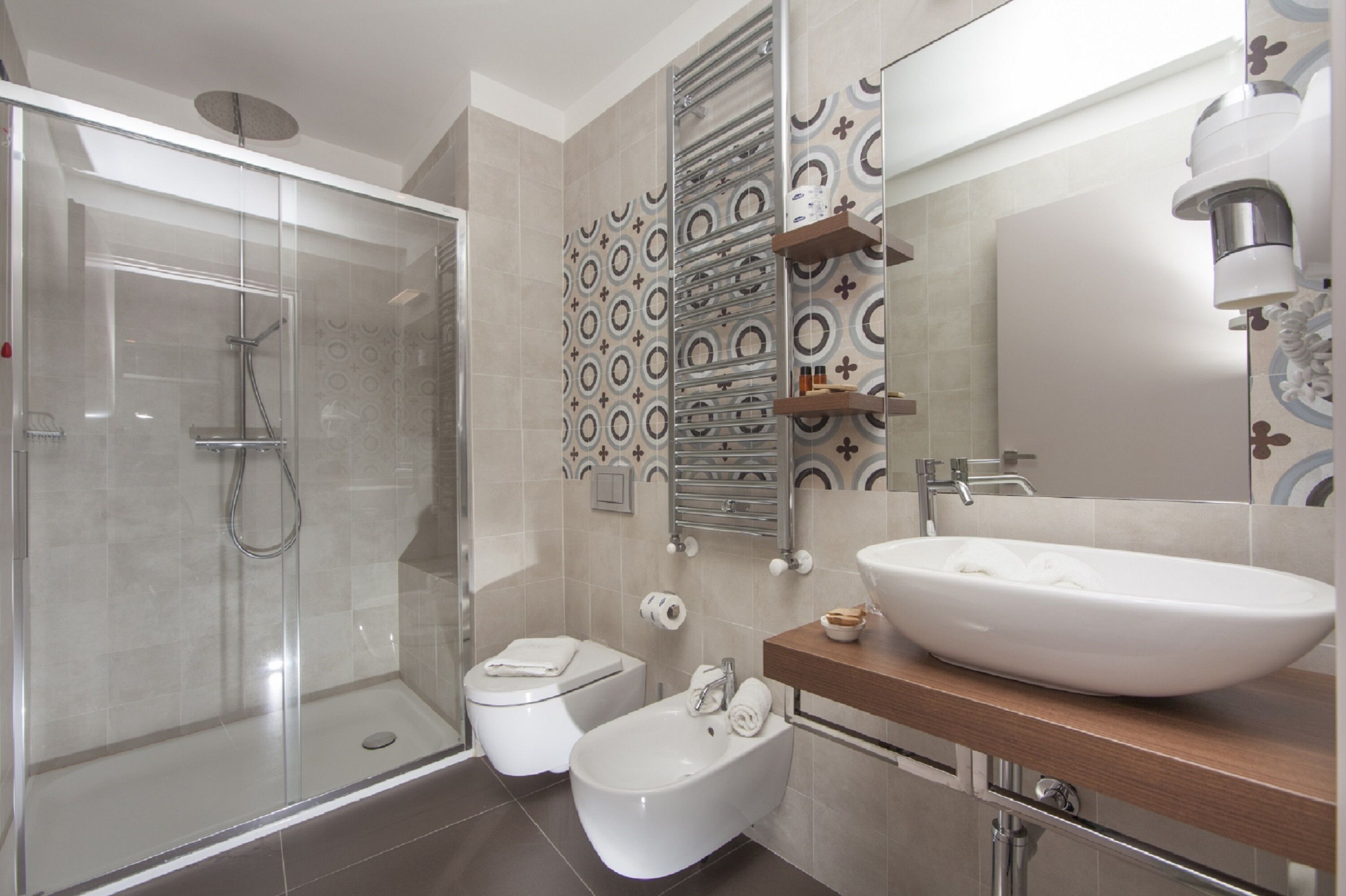 A modern bathroom with a glass shower enclosure, a bidet, a toilet, and a large sink with a mirror above.