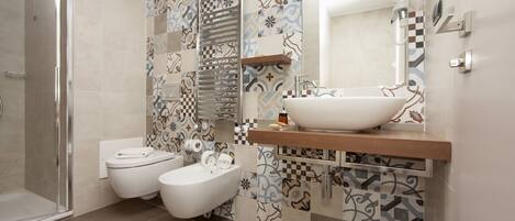 A modern bathroom with a shower, toilet, bidet, and a large vessel sink.