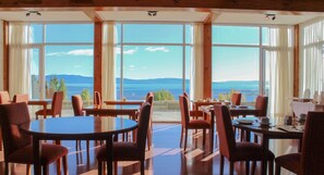 Enjoy a meal with a view of the lake and distant mountains from this dining area with large windows and comfortable seating.