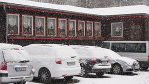 A building with multiple windows, some decorated with lights, and parked cars covered in snow. - Pension Waldoase Hirschbüchenkopf (Harzgerode)