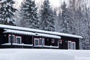 A cabin with a snow-covered roof and windows, surrounded by snow-laden trees. - Pension Waldoase Hirschbüchenkopf (Harzgerode)
