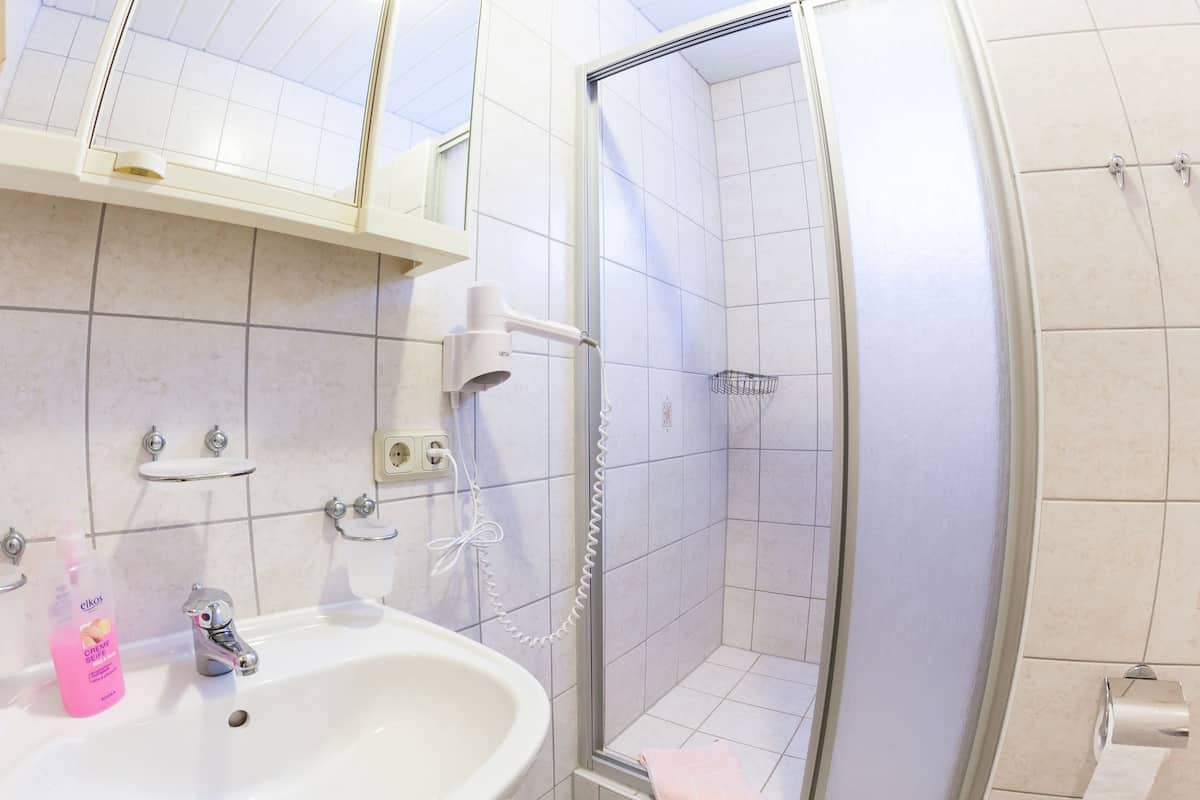 A bathroom with a sink, mirror, and shower.