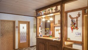 A reception area with a wooden counter, a mirror, and various decorative items. - Pension Waldoase Hirschbüchenkopf (Harzgerode)