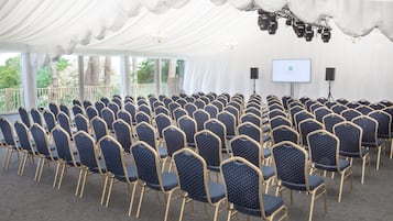 Un espacio para eventos con carpas, filas de sillas y una pantalla de proyección.