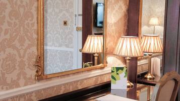 Ein Hotelzimmer mit einem großen Spiegel, zwei Lampen, einem Schreibtisch und einem Stuhl.