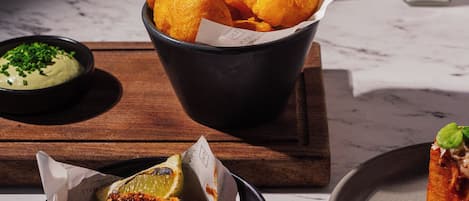 A table with a bowl of fried items, a bowl of green sauce, and a plate with a red sauce and garnish.