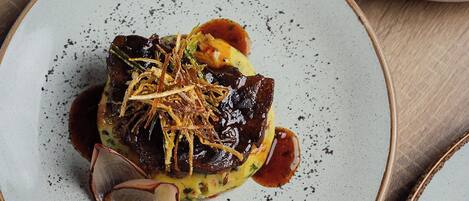 Une assiette contenant un plat, peut-être un steak, garni d’oignons frits et d’une tranche d’oignon rouge.