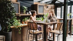 A café with wooden furniture, potted plants, and a large window. - Long John’s Hotel (Amersfoort)