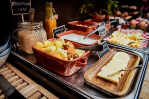 A buffet with various food items including fruits, cheese, and yogurt.