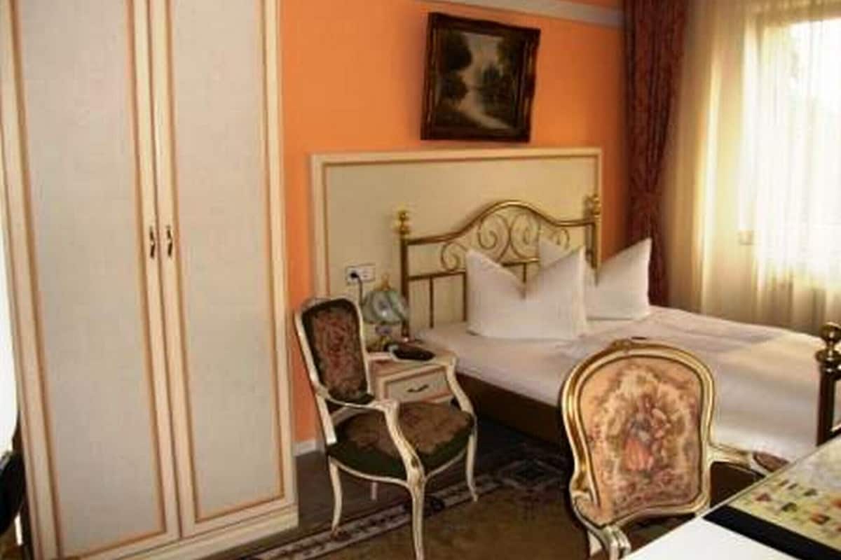 Een hotelkamer met een bed, een kledingkast, twee stoelen en een tafel.