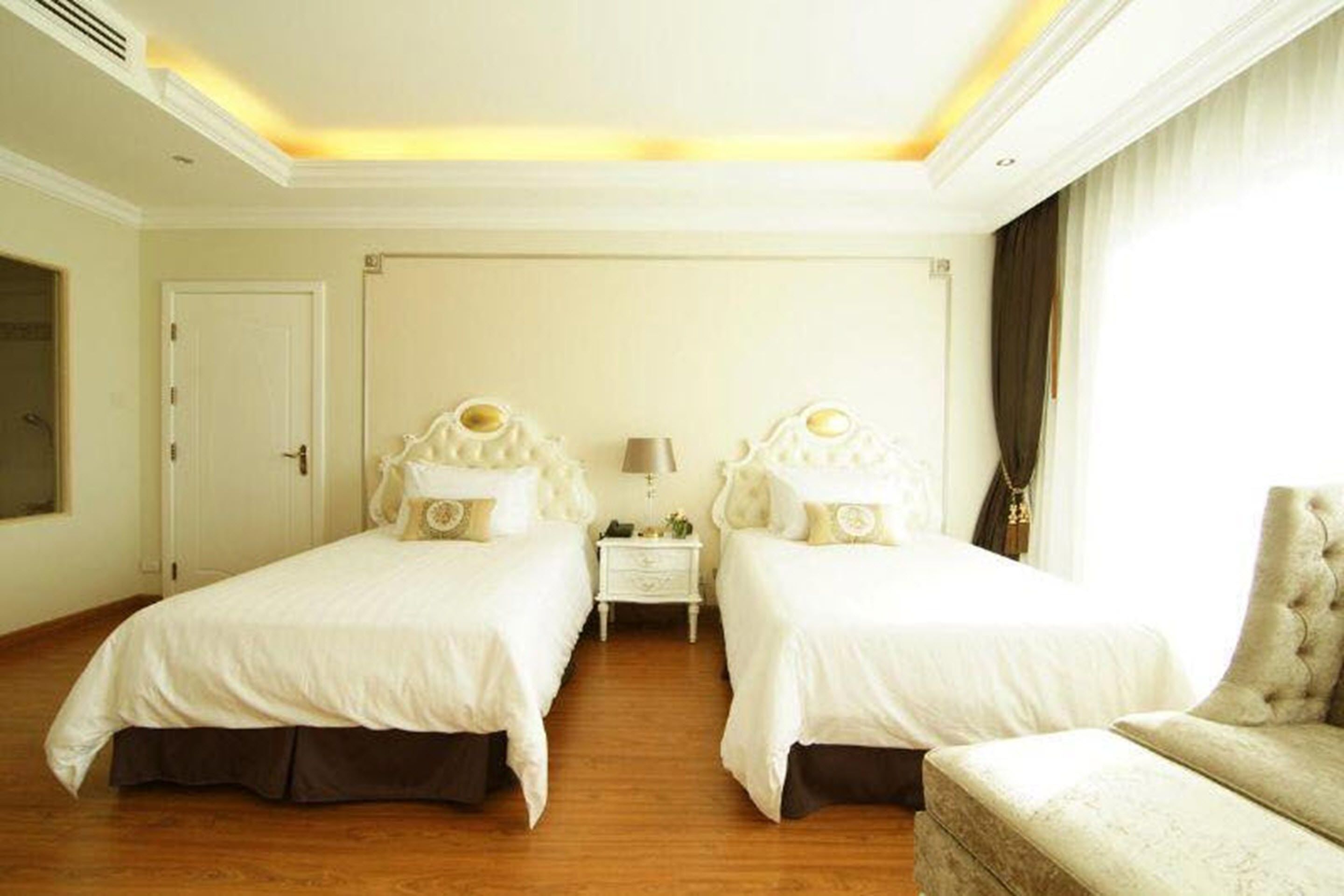 Ein Hotelzimmer mit zwei Betten, einem Nachttisch, einer Lampe und einem Sessel.