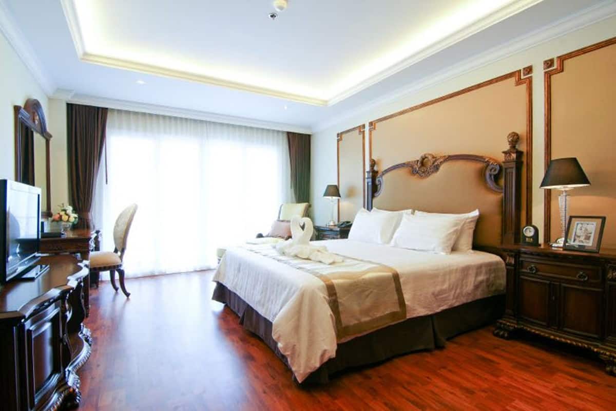 A spacious hotel room with a large bed, a desk, and a chair.