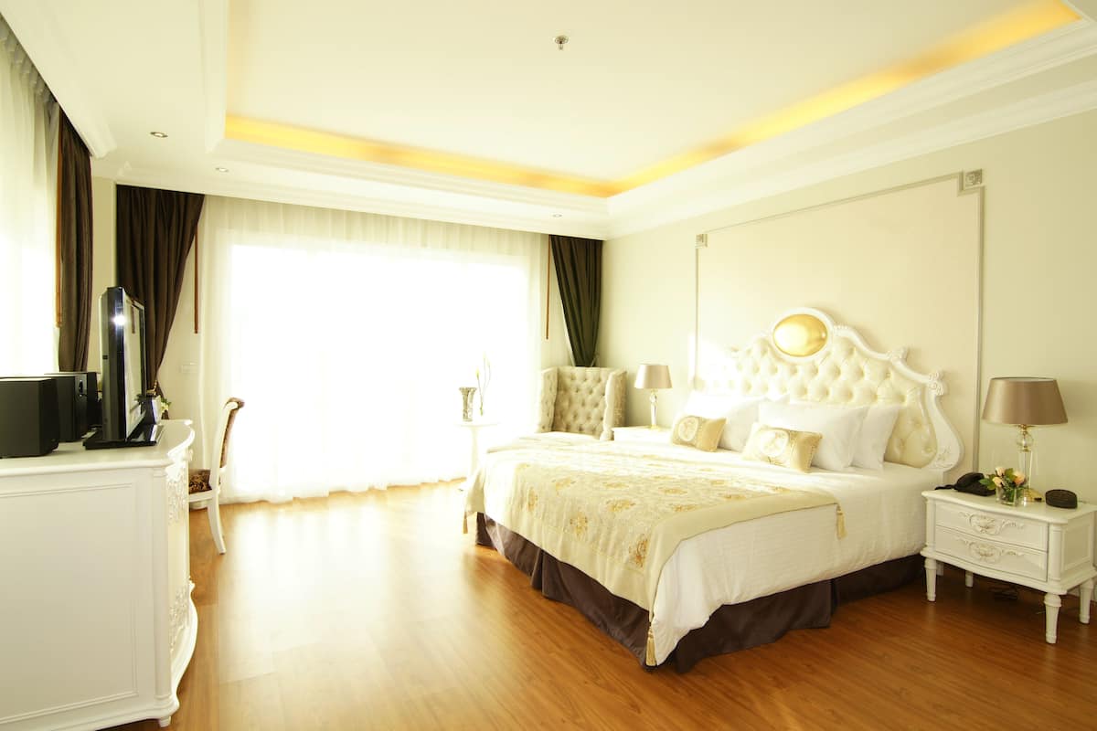 A spacious bedroom with a large bed, a bedside table with a lamp, and a dresser.