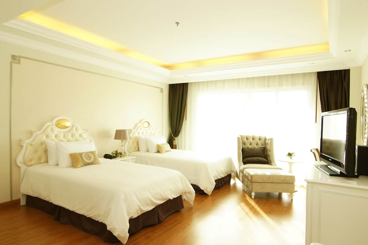 A hotel room with two beds, a television, a chair, and a small table.
