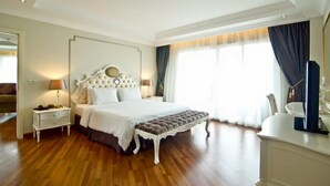 Um quarto espaçoso com uma cama grande, uma mesa de cabeceira, um banquinho e um armário.