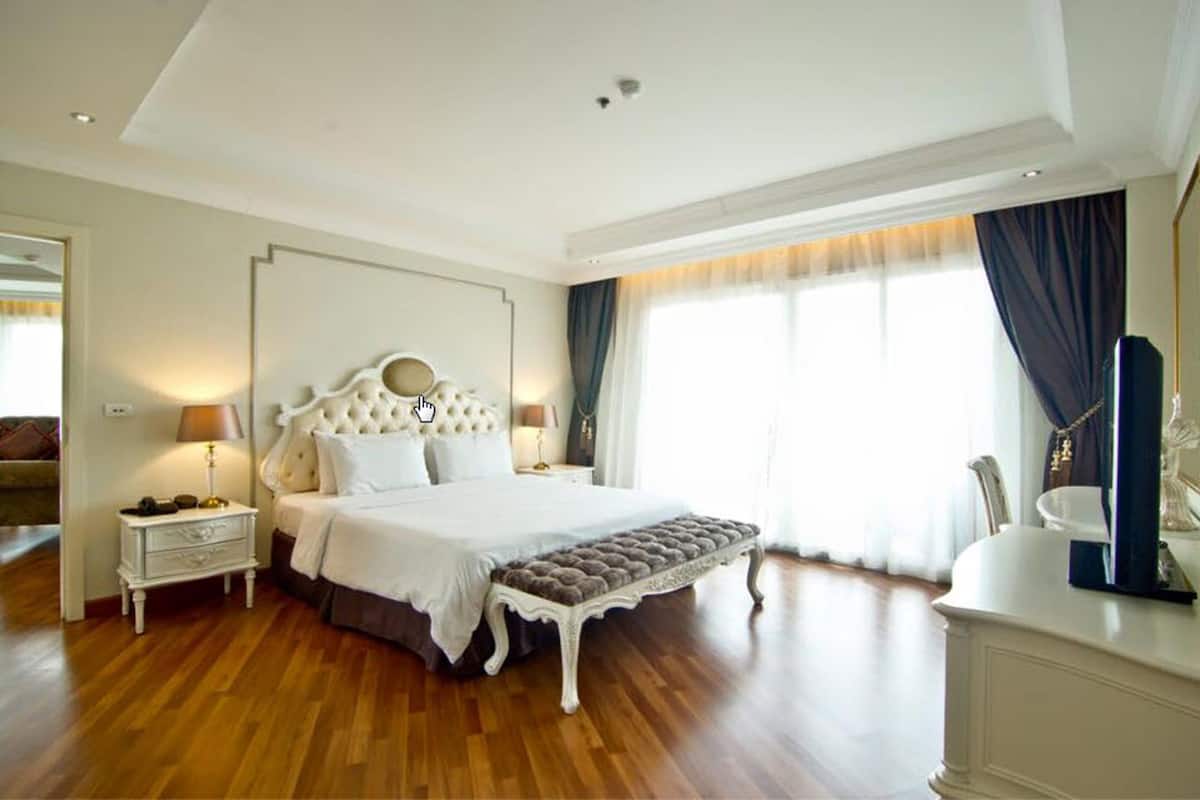 A spacious bedroom with a large bed, a nightstand, a bench, and a dresser.
