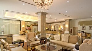 Um lobby luxuoso com um lustre imponente, mobiliário elegante e design clássico.