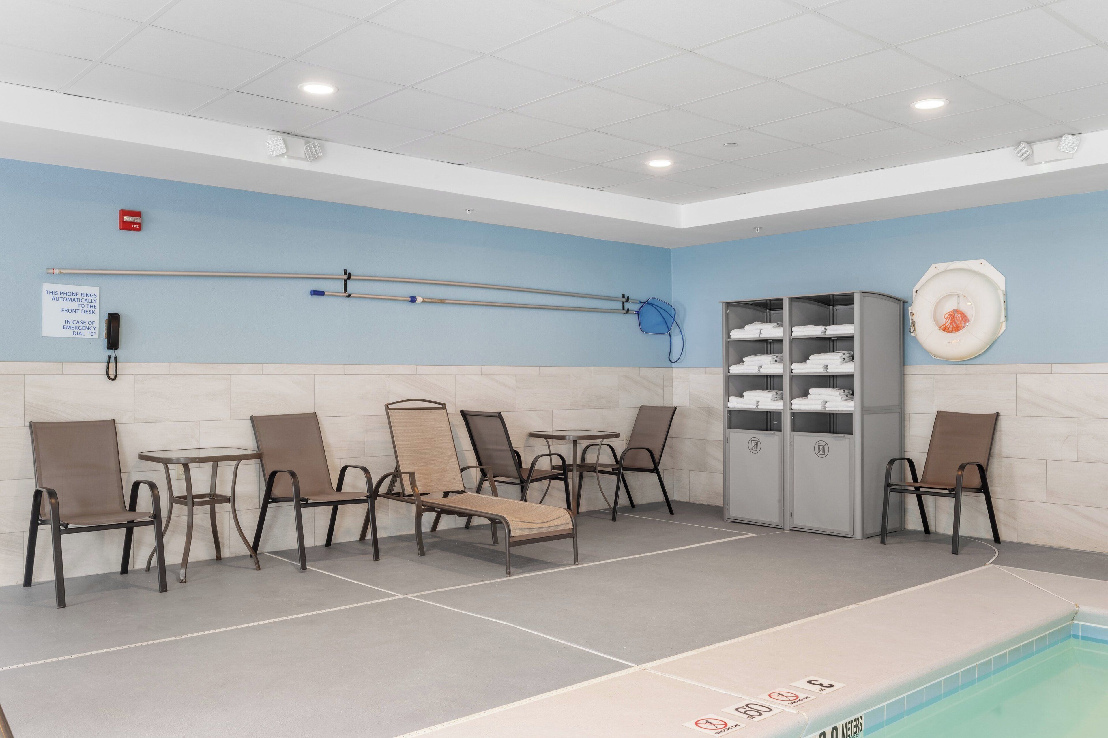 A pool area with lounge chairs, a pool table, and a towel rack.
