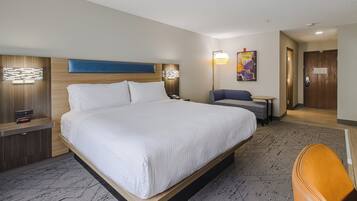Ein Hotelzimmer mit einem großen Bett, einem Schreibtisch, einem Stuhl, einer Lampe und einem Gemälde an der Wand.