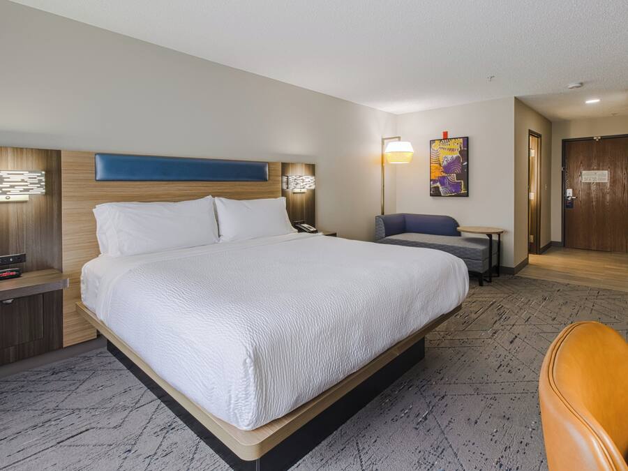 Ein Hotelzimmer mit einem großen Bett, einem Schreibtisch, einem Stuhl, einer Lampe und einem Gemälde an der Wand.