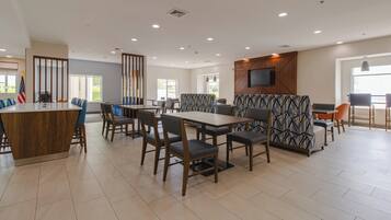 A modern dining area with a central island, booths, and a television mounted on the wall.