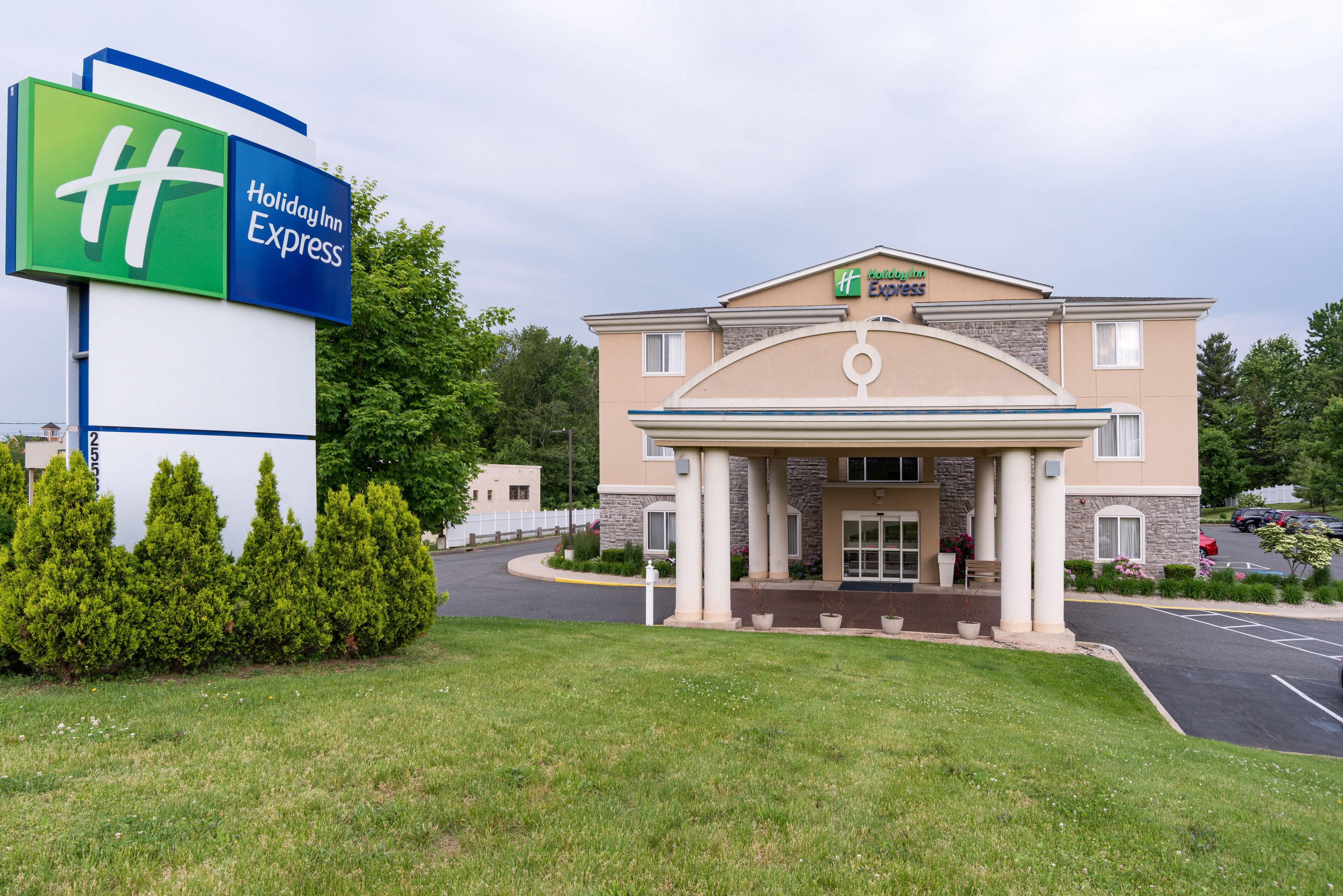 Een Holiday Inn Express gebouw met een groot bord, een parkeerplaats en een verzorgd gazon.