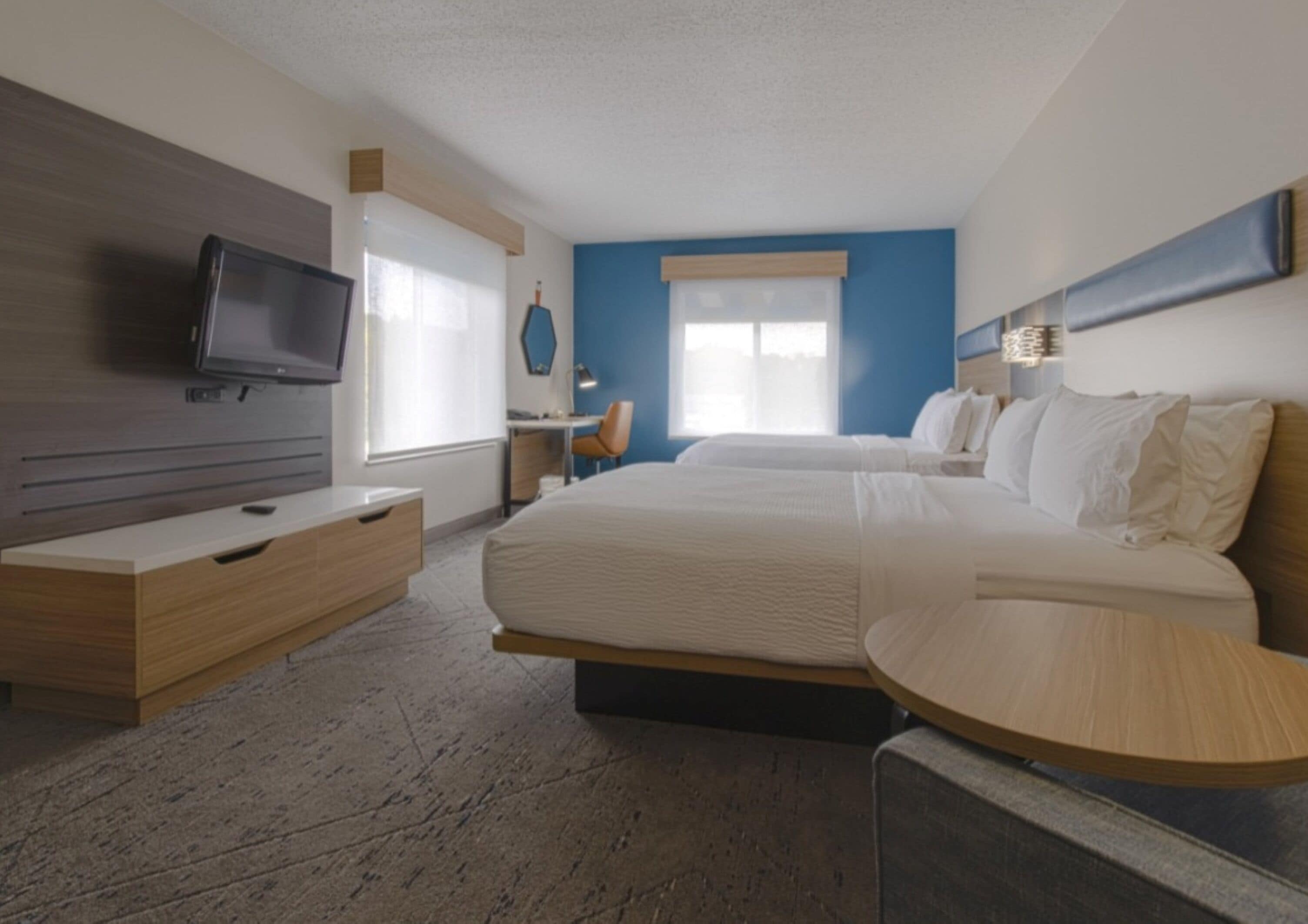 Ein Hotelzimmer mit einem großen Bett, einem Fernseher, einem Schreibtisch und einem Sessel.