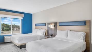 A hotel room with two beds, a large window, and a view of the outdoors.