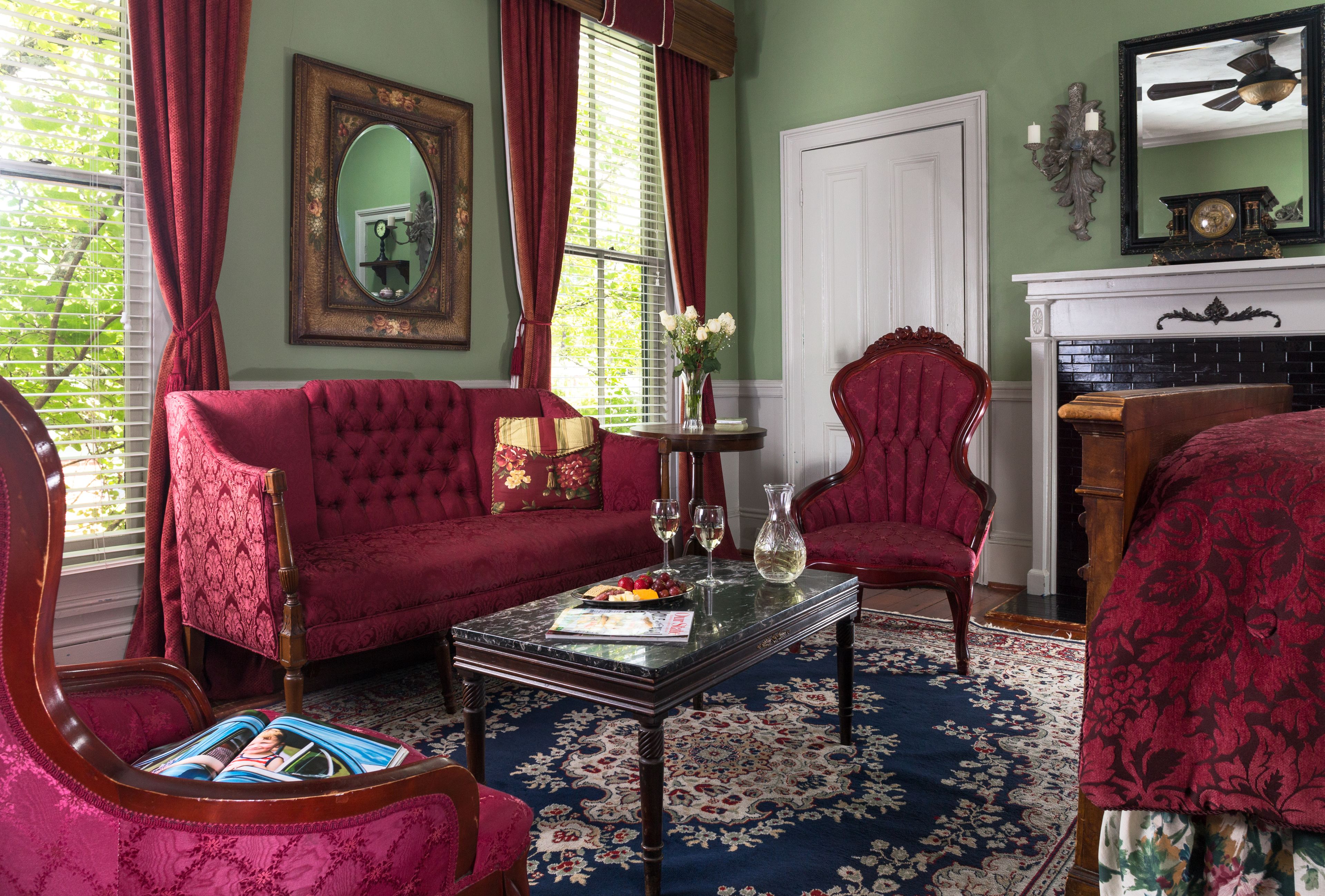 A room with a red sofa, a matching armchair, a coffee table, and a fireplace.