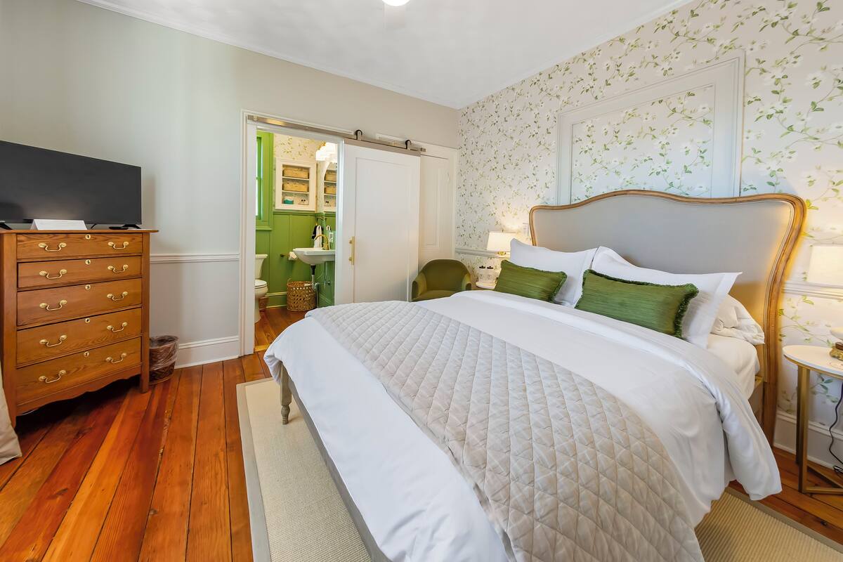 Een slaapkamer met een groot bed, een houten dressoir en een televisie op het dressoir.