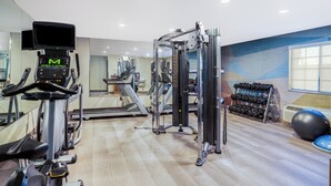 A gym with cardio equipment, weight machines, and dumbbells.