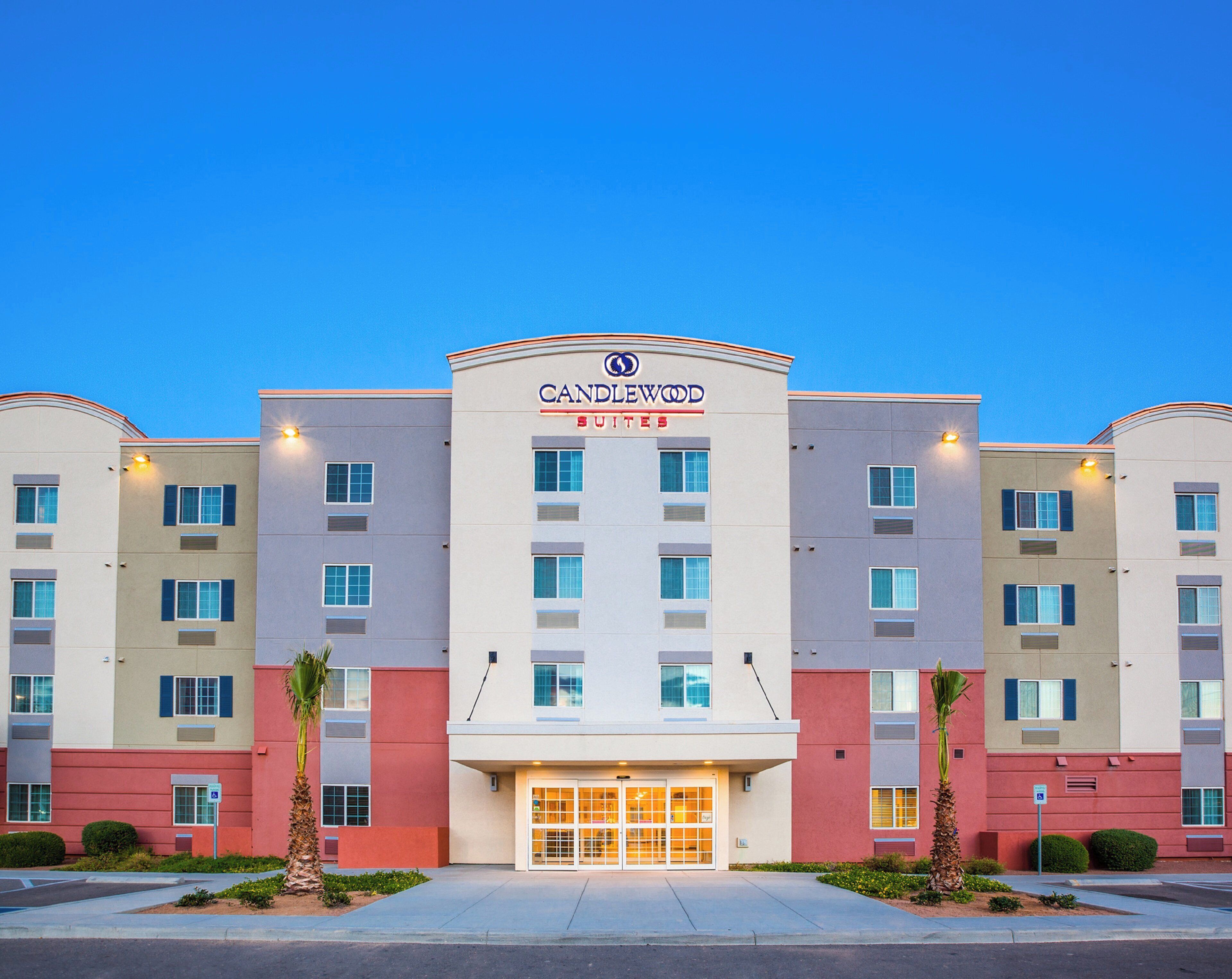 Een meerhoog hotel met een opvallend 'CANDLEWOOD SUITES' bord bij de ingang.