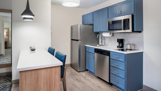 A modern kitchen with blue cabinets, stainless steel appliances, and a white countertop.