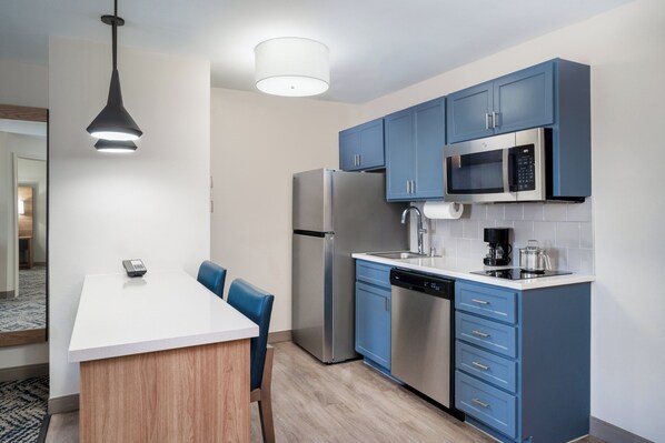A modern kitchen with blue cabinets, stainless steel appliances, and a white countertop. - Candlewood Suites El Paso by IHG (El Paso)