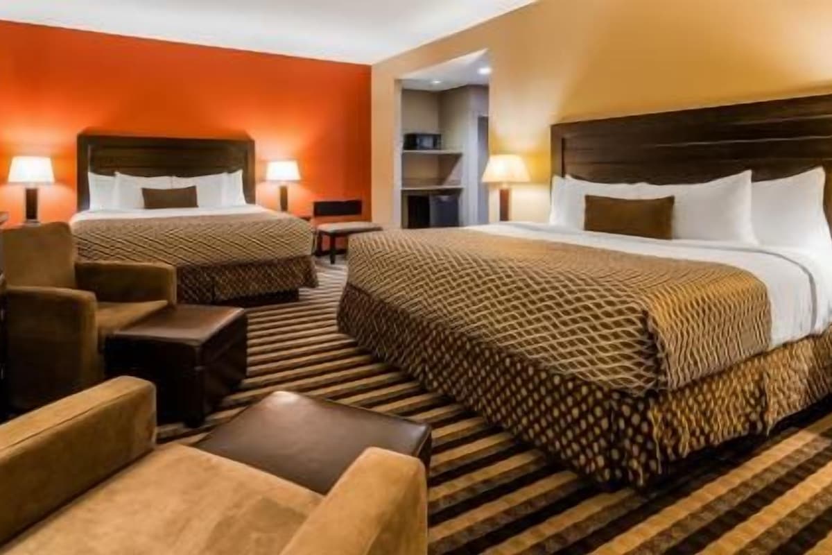 A hotel room with two beds, a TV, a desk, and a chair.
