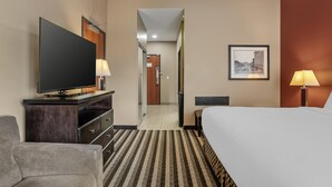 Ein Hotelzimmer mit einem Bett, einem Fernseher auf einem Schminktisch, einem Schreibtisch und einem Stuhl.