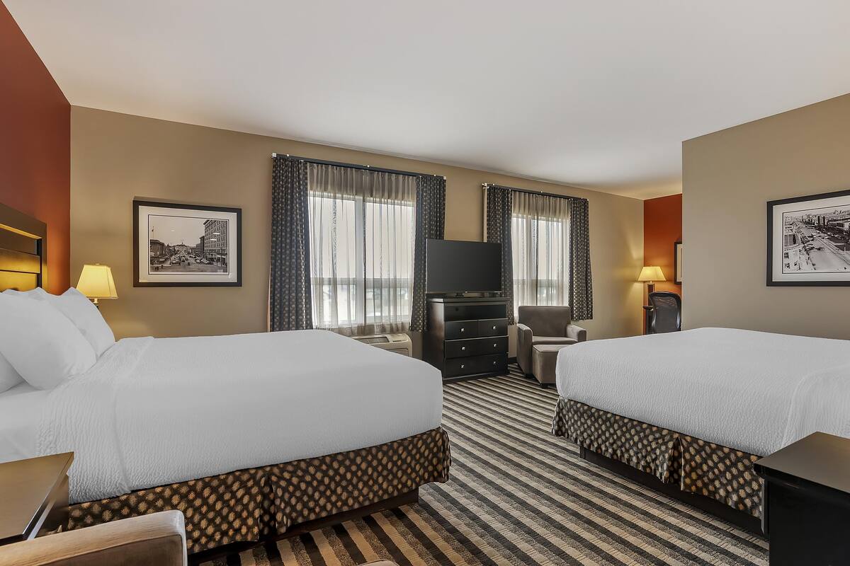 A hotel room with two beds, a TV, a desk, and a chair.