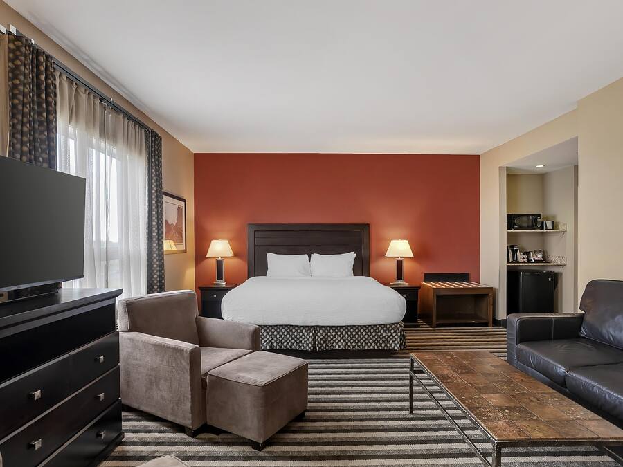 A hotel room with a large bed, a TV, a sofa, a desk, and a dresser.