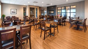 Ein geräumiges Restaurant mit mehreren Tischen und Stühlen, großen Fenstern und einem modernen Interieur.
