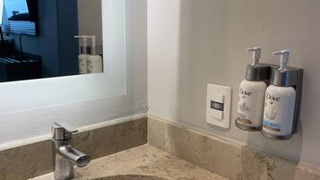 A bathroom with a white sink, a mirror, and two Dove lotion dispensers on the wall.