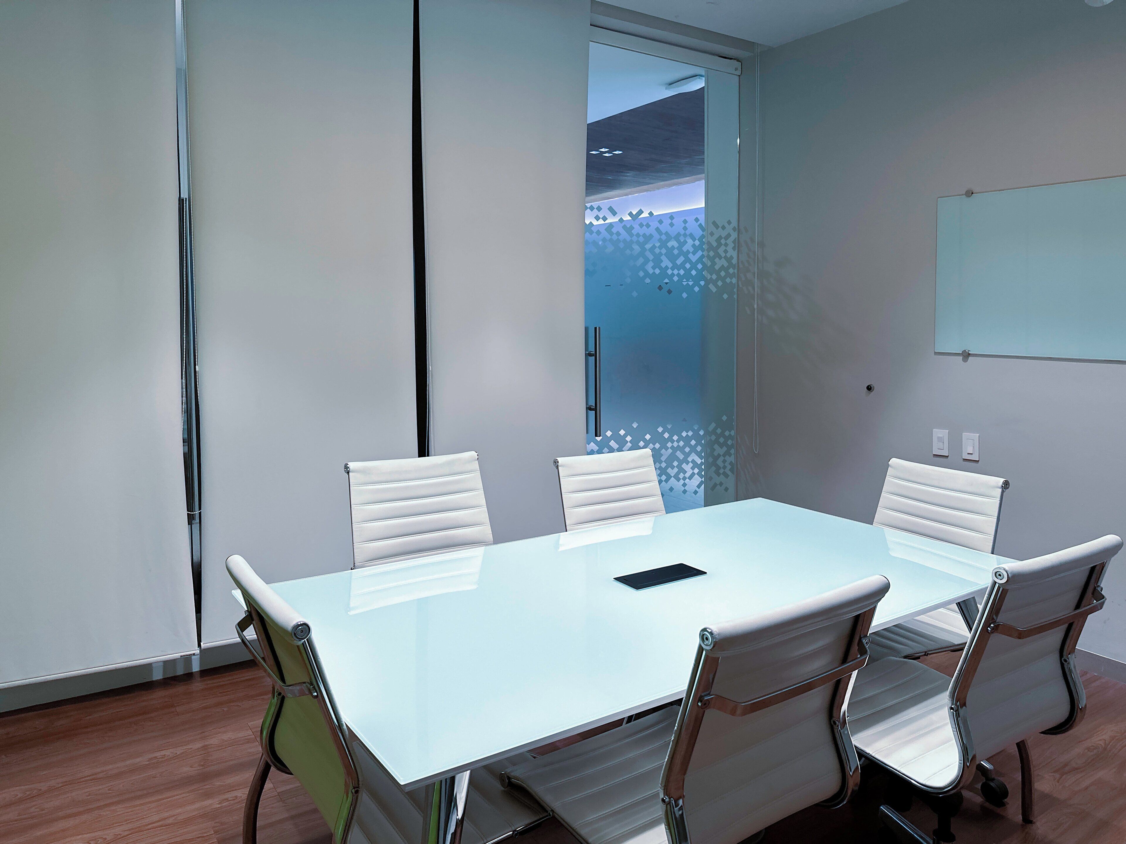 A conference room with a white table and four white chairs.