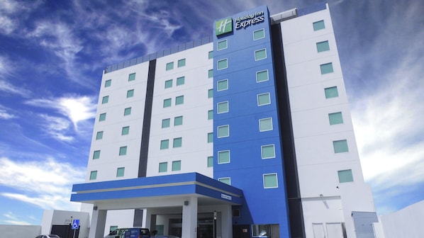 A Holiday Inn Express hotel with a modern design, featuring a blue and white color scheme, multiple floors, and a parking area.