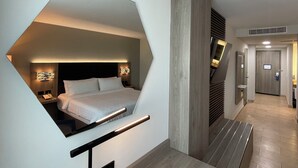 A modern hotel room with a unique geometric design, a large bed, and a built-in desk area. - Holiday Inn Express Mérida by IHG (Mérida)