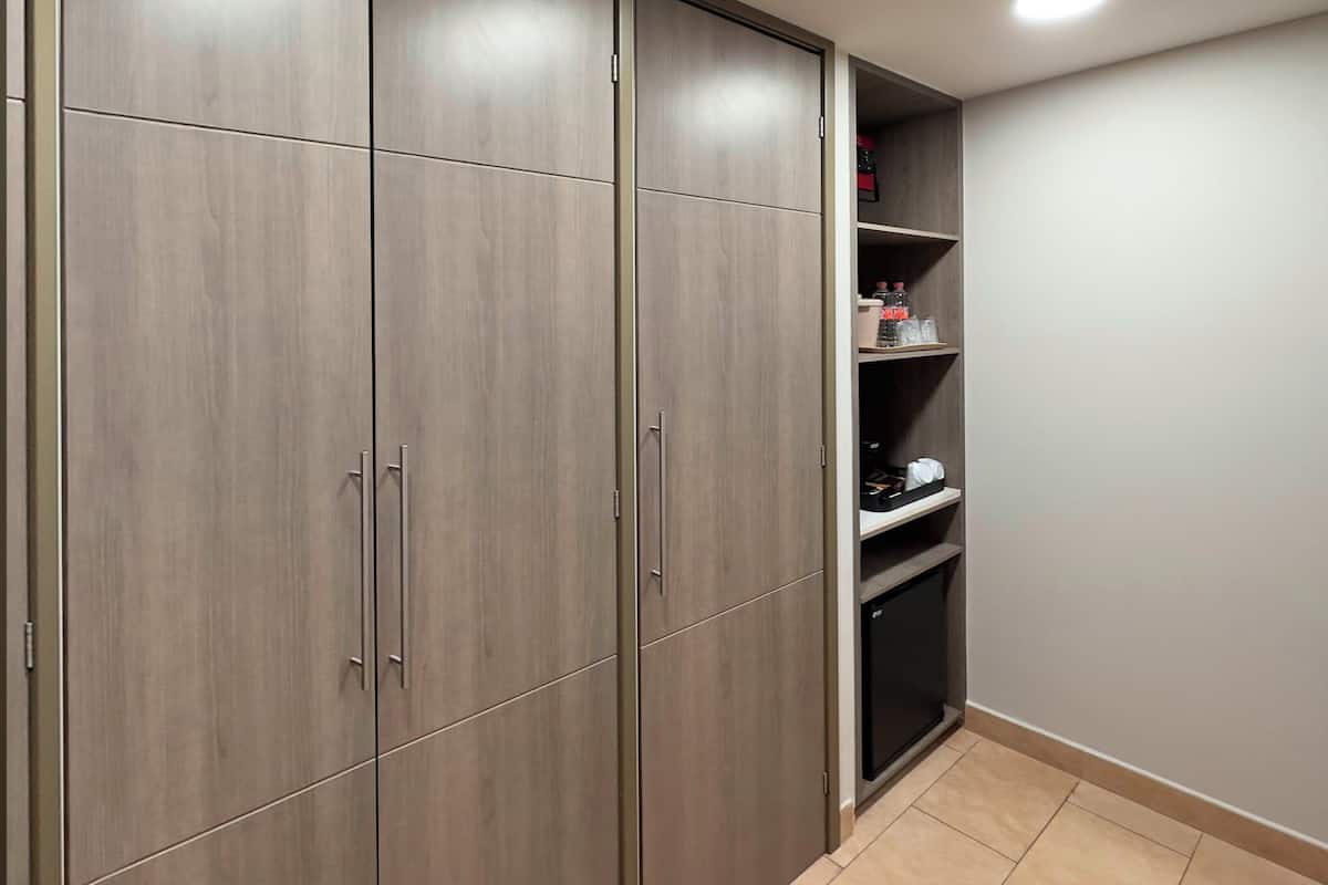 A walk-in closet with wooden doors and shelves, containing various items.