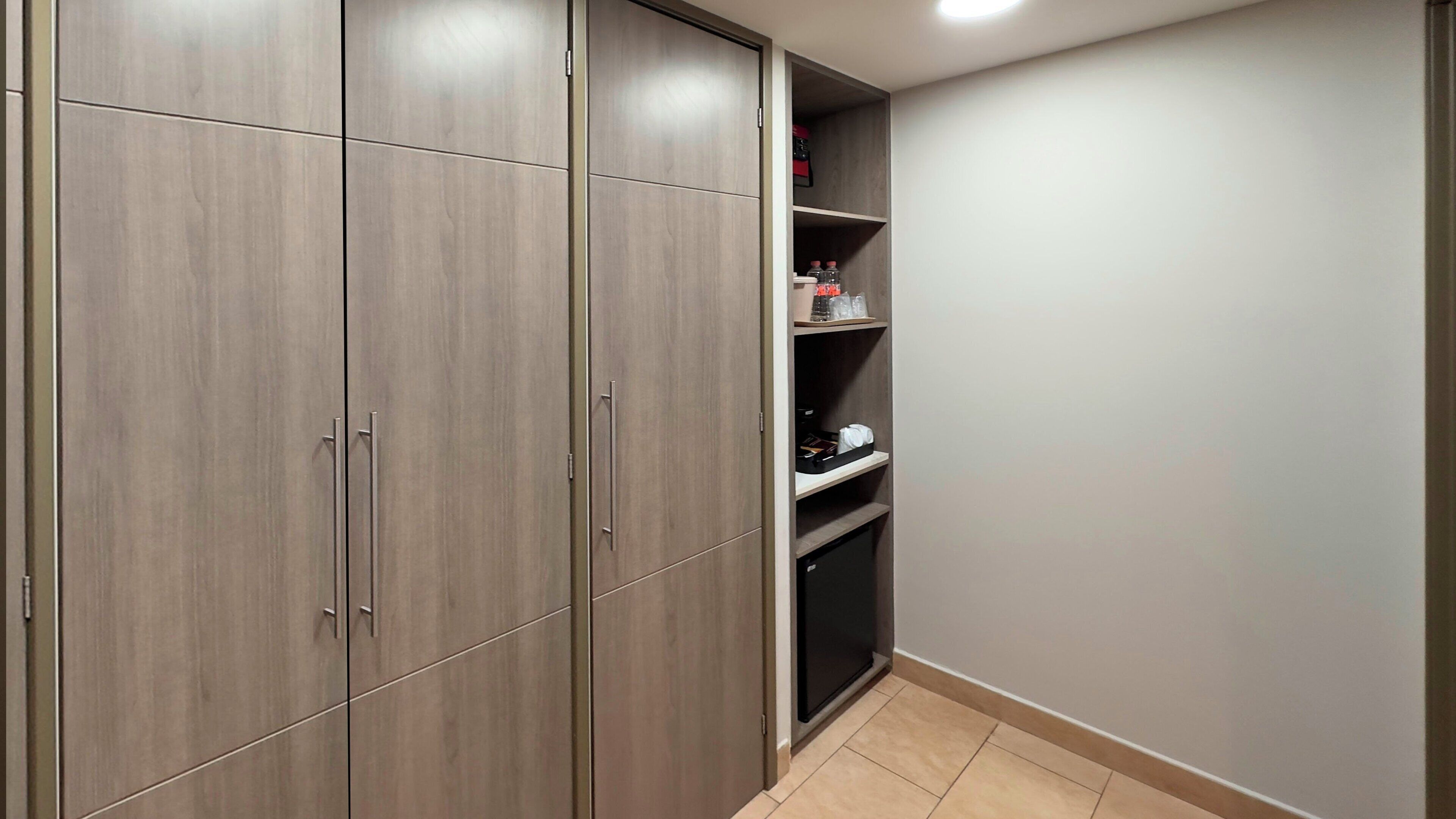 Ein begehbarer Kleiderschrank mit Holztüren und Regalen, gefüllt mit verschiedenen Gegenständen.