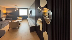 A modern living room with a sofa, chairs, a coffee table, and a large mirror. - Holiday Inn Express Mérida by IHG (Mérida)