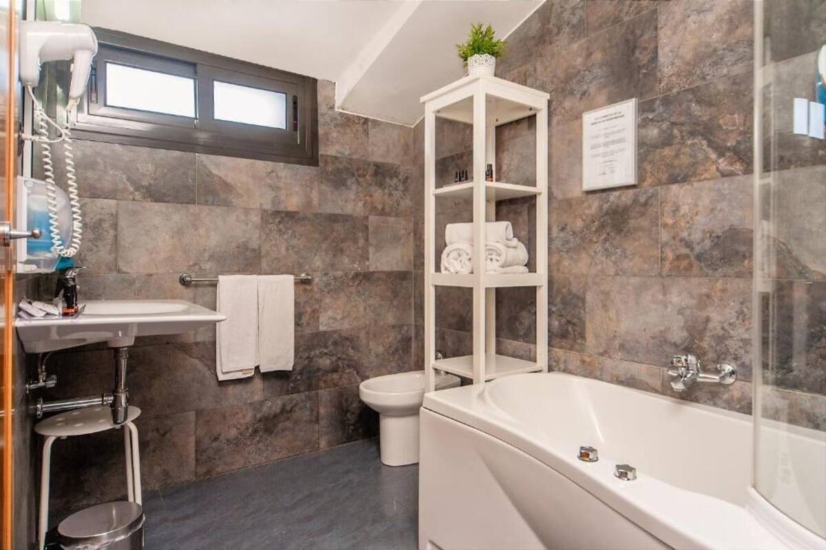 A modern bathroom with a bathtub, a toilet, a sink, and a towel rack.