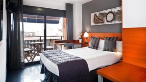 Quarto de hotel com cama, escrivaninha, cadeira e varanda com vista.