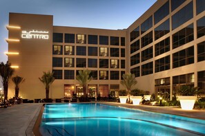 A hotel with a swimming pool, palm trees, and a modern building facade. - Centro Sharjah by Rotana (Sharjah)